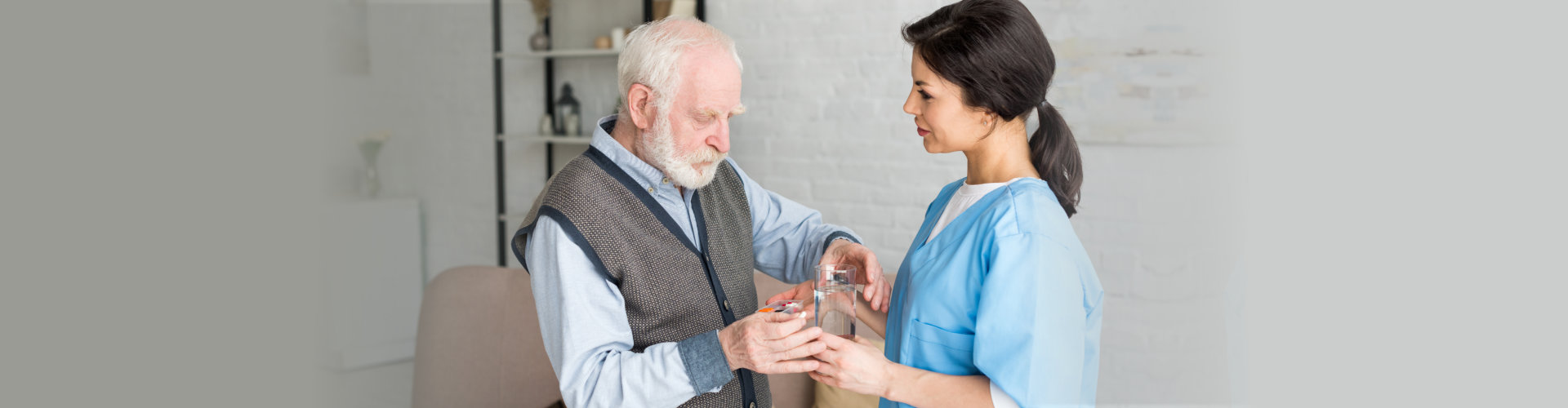 a caregiver assisting the elderly man on the medicine